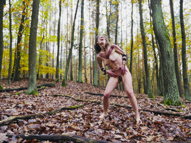 Wilde Frau, die nackt im Wald tanzt