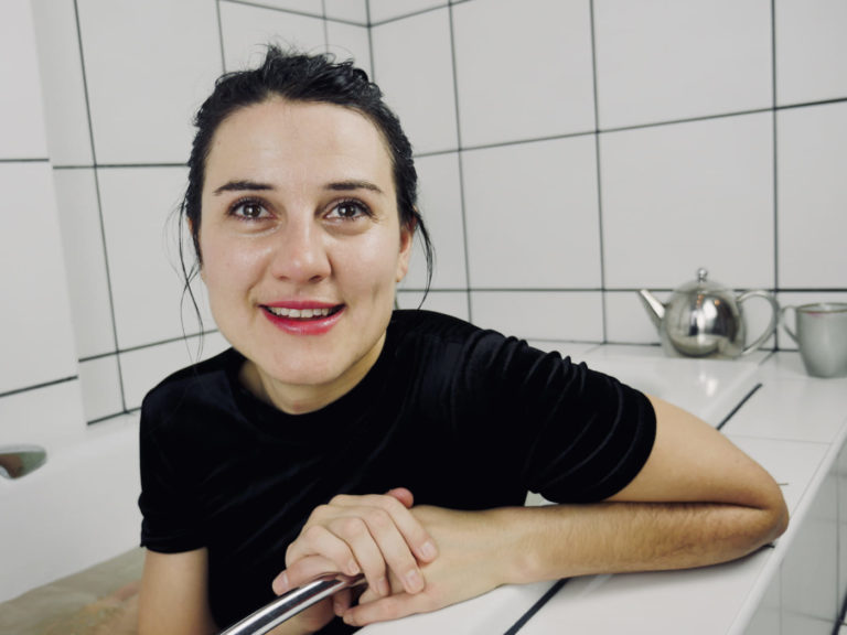 Frau sitzt mit schwarzem Kleid in der Badewanne